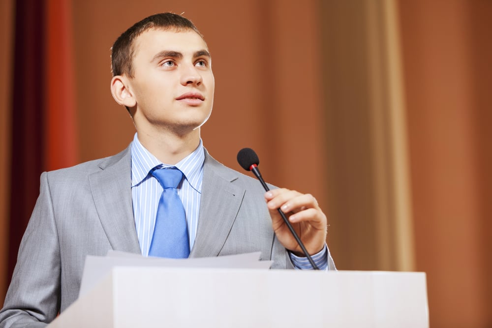 Businessman standing on stage and reporting for audience